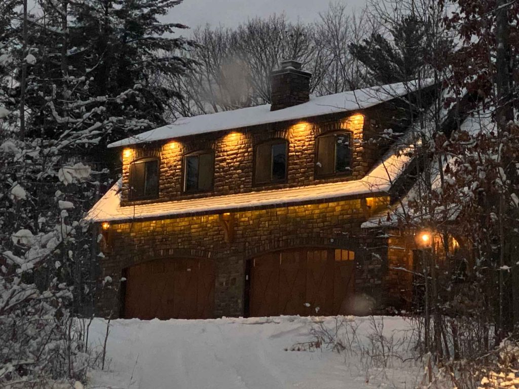 Two-car garage with decorative stone facade in snowy landscape
